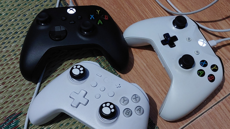 Two first-party Xbox controllers with wired USB cables and an additional third-party controller.