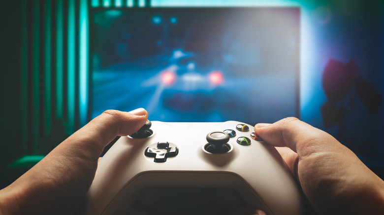 A mock-up of a person using a white Xbox controller wirelessly while playing a game.