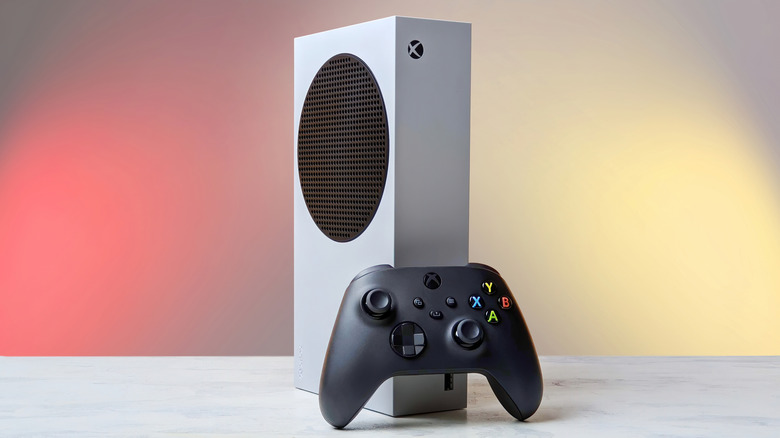 A white Xbox Series S with a black Xbox controller sitting in front of it.