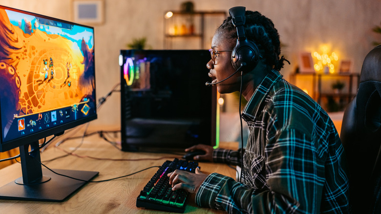 A gamer playing an RPG on a gaming PC while seated at a desk.