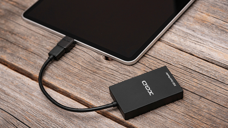 An external SSD plugged into an iPad resting on an outdoor table.