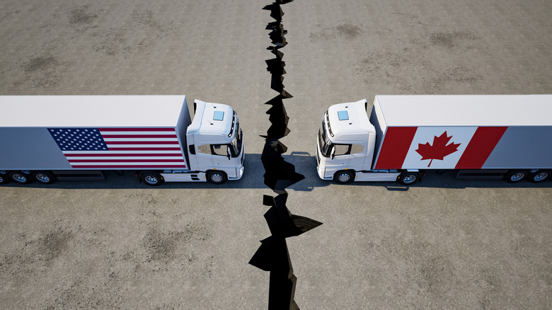 Two semi-trucks, one with a US flag and the other with a Canadian flag, head to head.