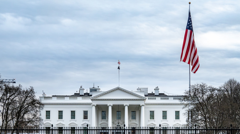 Photo of the North side of the White House on an overcast day with an American flag raised.
