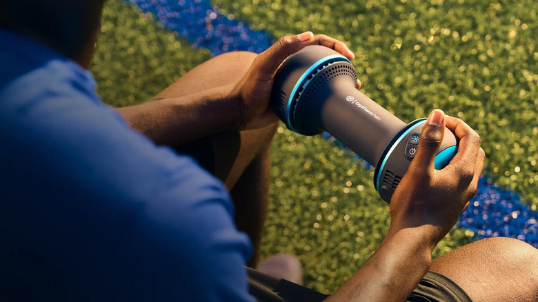 Someone using Therabody's CryoTherm Palm device.