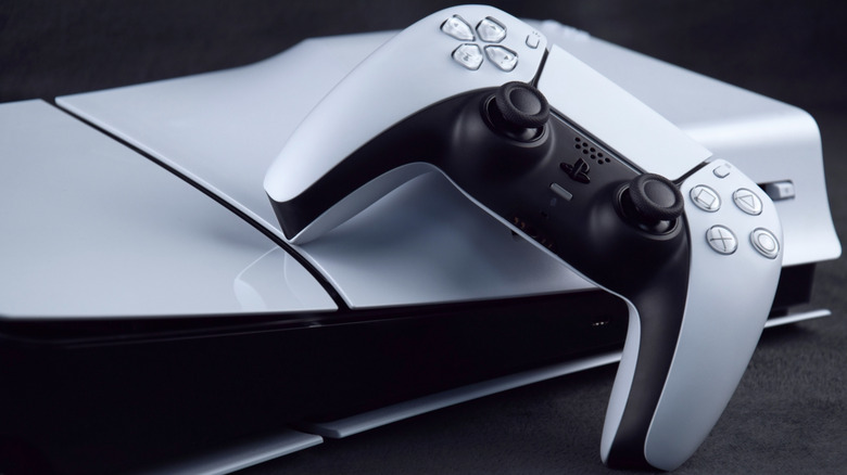 A PlayStation 5 console laying flat, with a DualSense Wireless Controller leaning on it.
