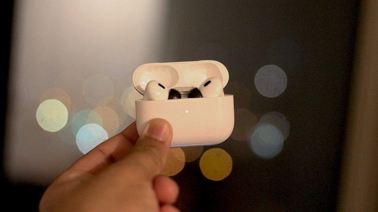 Person holding up a pair of AirPods Pro.