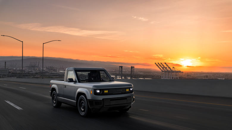 A gray Slate drives across a bridge at sunset.