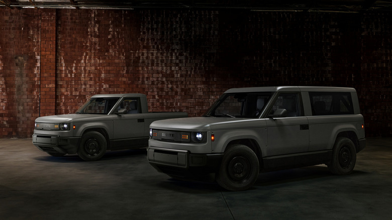A Slate Truck and SUV stand in a shadowy, brick-walled warehouse.