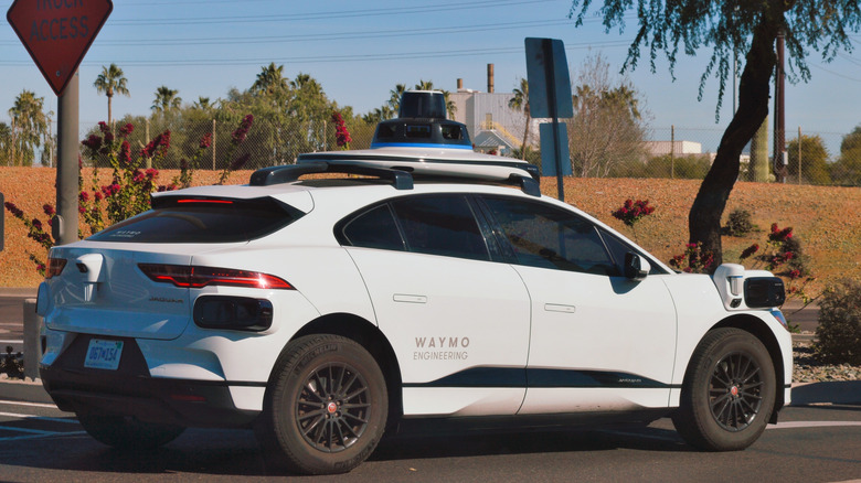 Photo of a white Waymo robotaxi on the road in the desert setting of Phoenix, Arizona.