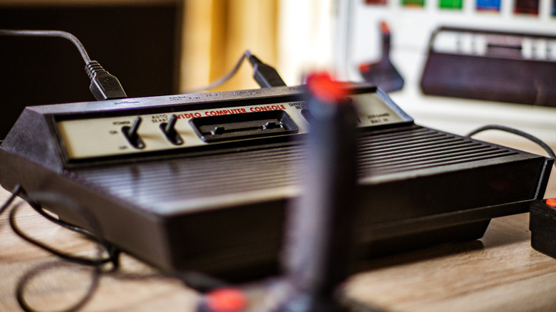 Close-up photo of an Atari 2600 video game system with a blurry joystick visible in the foreground and the console's box blurry in the background.