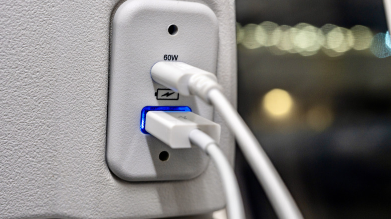 USB cables plugged into the back of a plane seat.