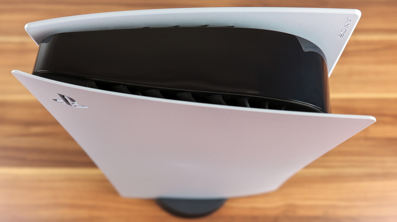 Top-down view of a PlayStation 5 positioned vertically, with its stand on the bottom.