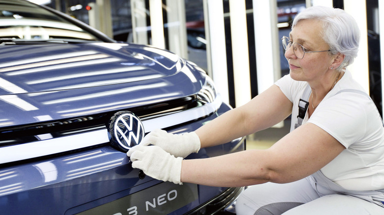 a person putting a Volkswagen logo on a car