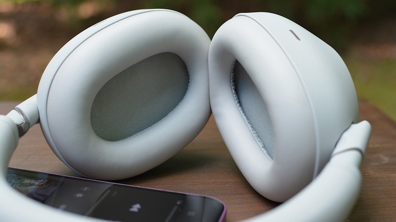 Closeup of the Sony WH-1000XM6 headphones on a table next to a phone.