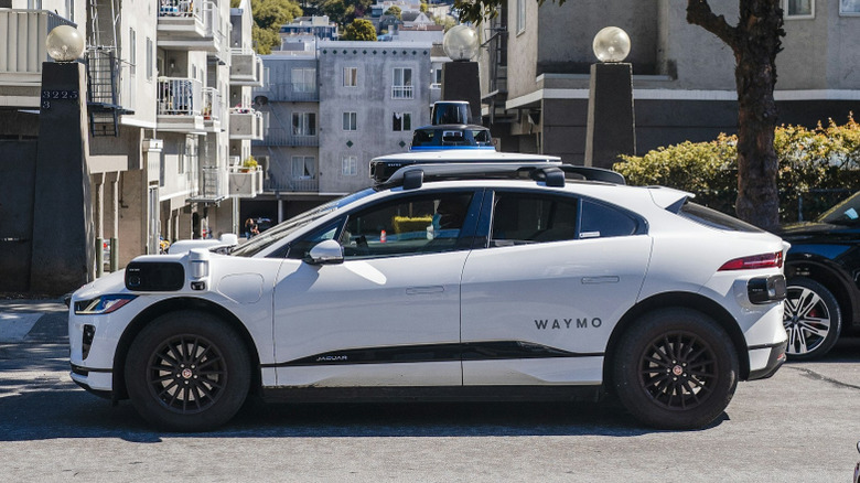 A white Waymo self-driving car on a street.
