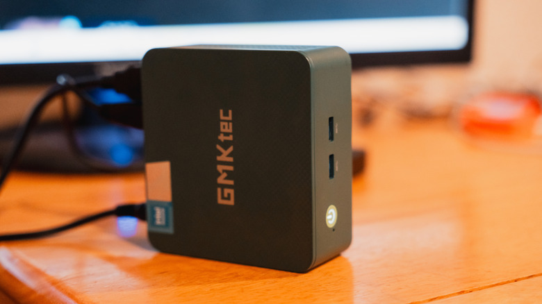 A GMKtec mini PC, positioned on its side on a desk.