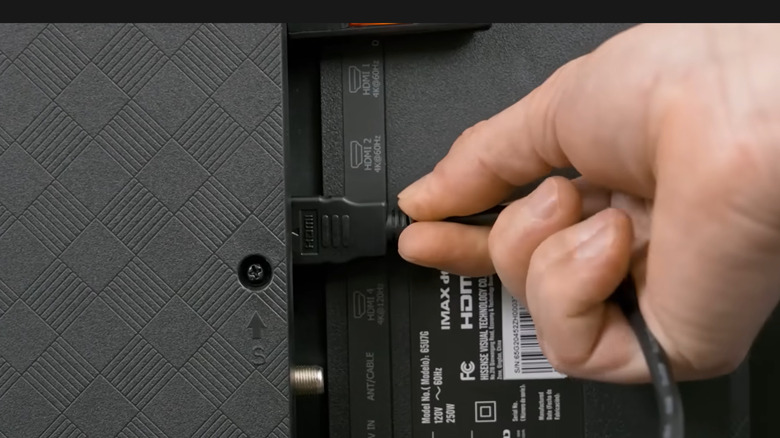 A hand plugs an HDMI cord into an HDMI port.