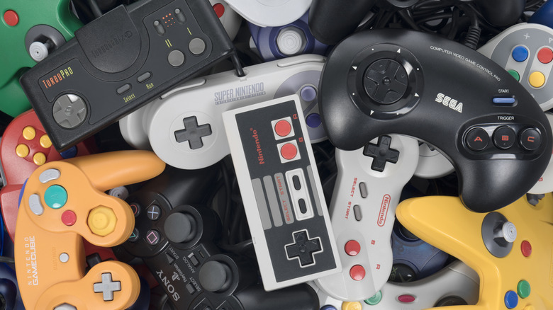 A bunch of retro game controllers piled together.