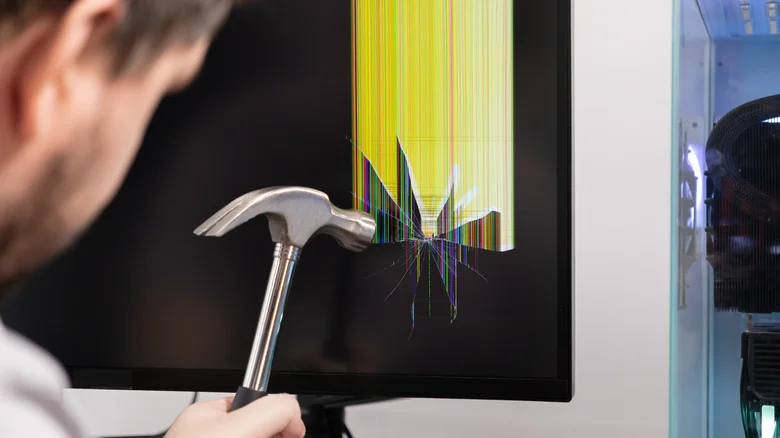 A person hitting a broken monitor with a hammer.