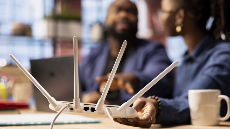 Woman holding a Wi-Fi 7 while sitting at desk.