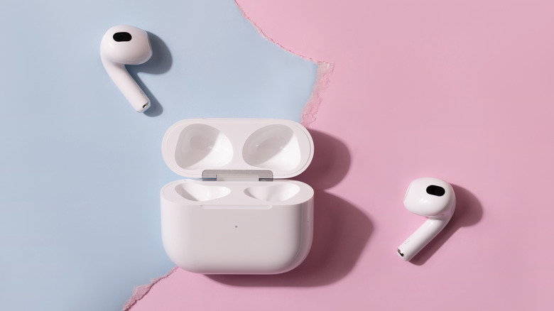 AirPods Pro 3 alongside their charging case on a pink and blue background.
