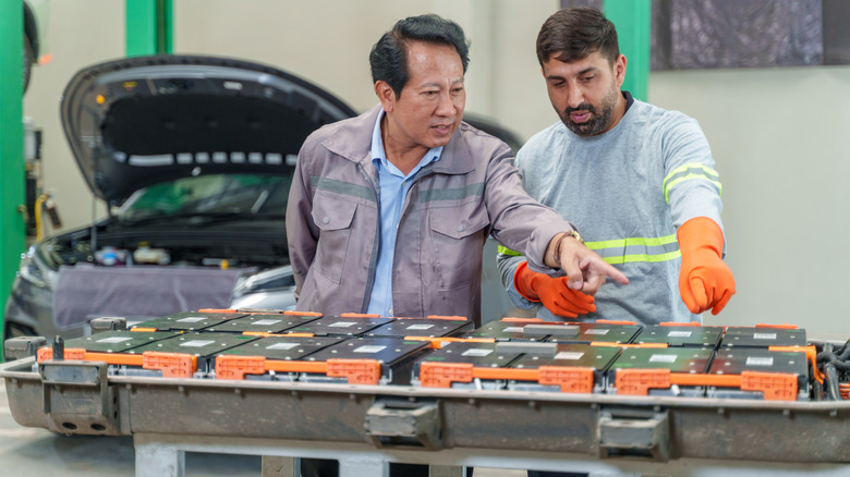 Technicians inspecting an EV car battery in a manufacturing facility or lab.