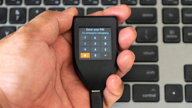 A Trezor hardware wallet in-hand with PIN input on-screen