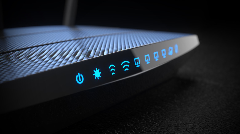 Front view of a router with a blue LED display and a dark background.