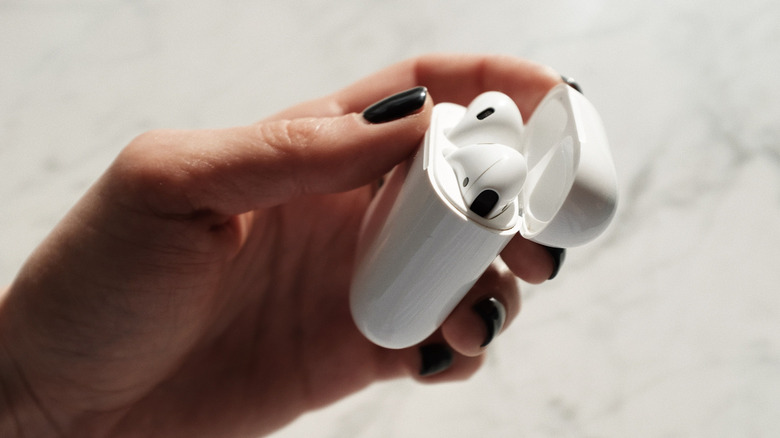 Woman's hand holding open case of AirPods