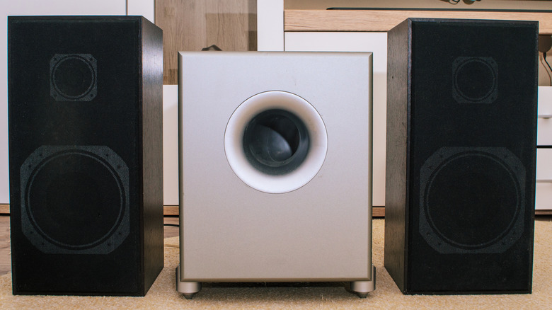 Gray subwoofer flanked by two black speakers.