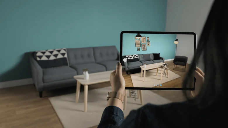 Person using a tablet to scan a living room with augmented reality room-mapping software.