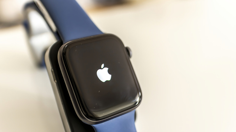 Blue Apple Watch displaying the Apple logo on its screen.