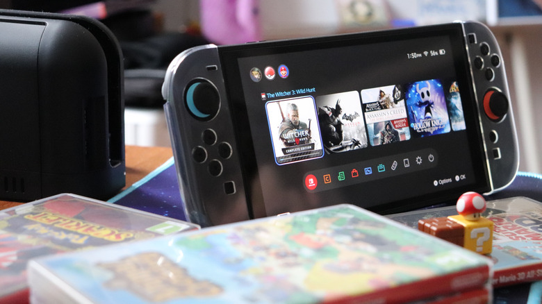 Photo of Nintendo Switch 2 handheld next to stack of games.