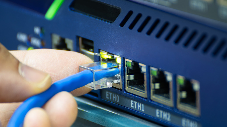 An Ethernet cable being plugged into the back of a network switch.