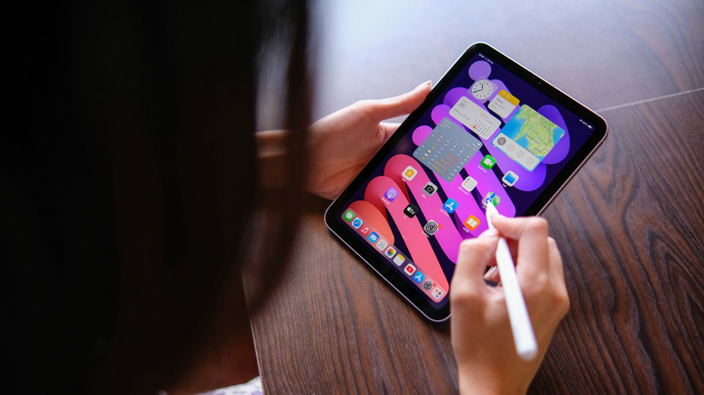 A person holding an iPad mini and an Apple Pencil.
