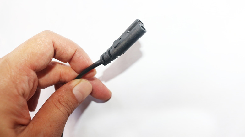 Person holding a C7 power cord.