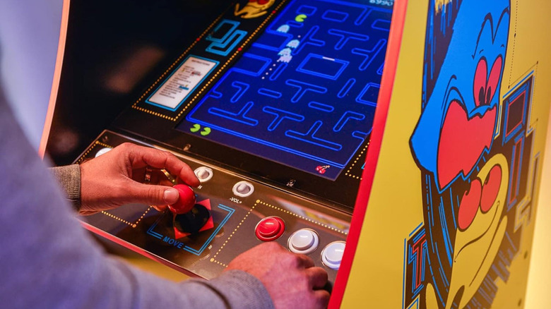 A person playing Pac-Man on an Arcade1Up arcade cabinet.