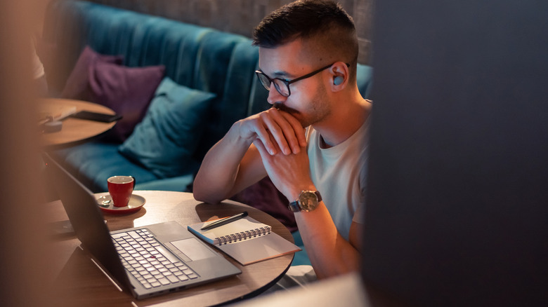 Image of man using wireless earbuds while watching a screen.