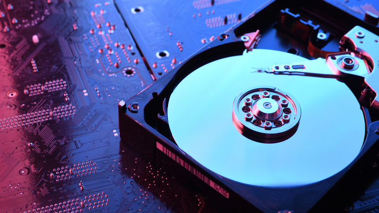 Open hard disk drive with an exposed platter resting on a computer circuit board.