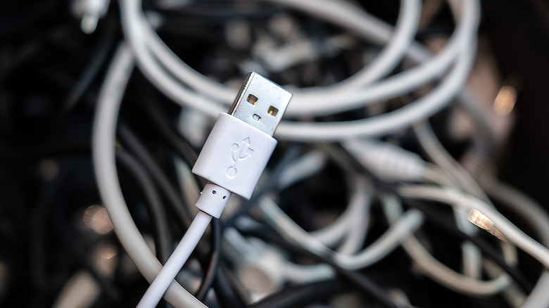 A USB-A cable with the USB trident logo clearly visible stands out against a backdrop of assorted messy cables.