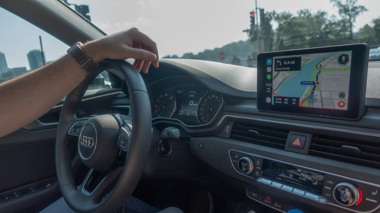 A person driving with navigation displayed on a screen mounted to the dash.