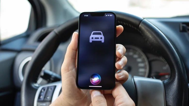 Siri on an iPhone showing the car icon, in front of a steering wheel.