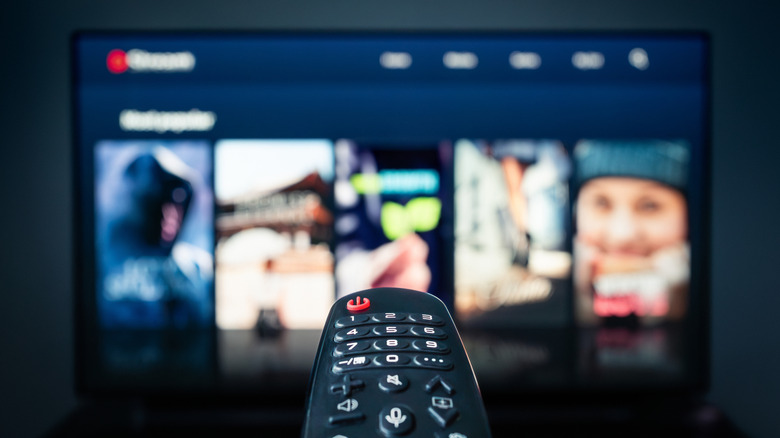 TV remote pointed toward a television displaying a blurred streaming service interface.