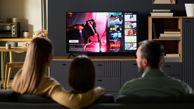 Family sitting on a couch and watching a streaming service interface on a television.