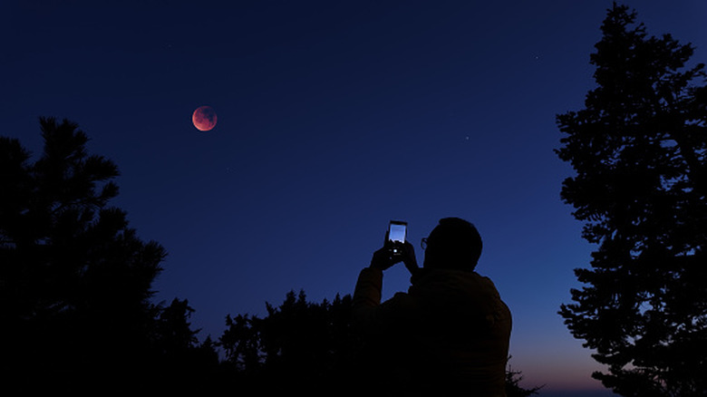 Person using smartphone to take a picture of the night sky.