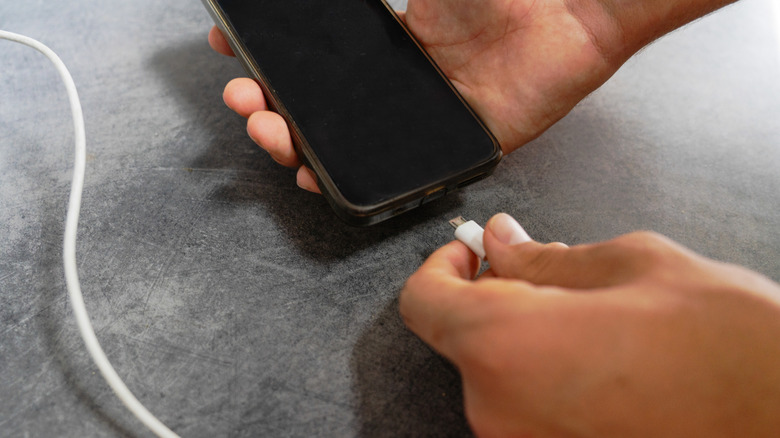 A person plugging a phone into a charger.