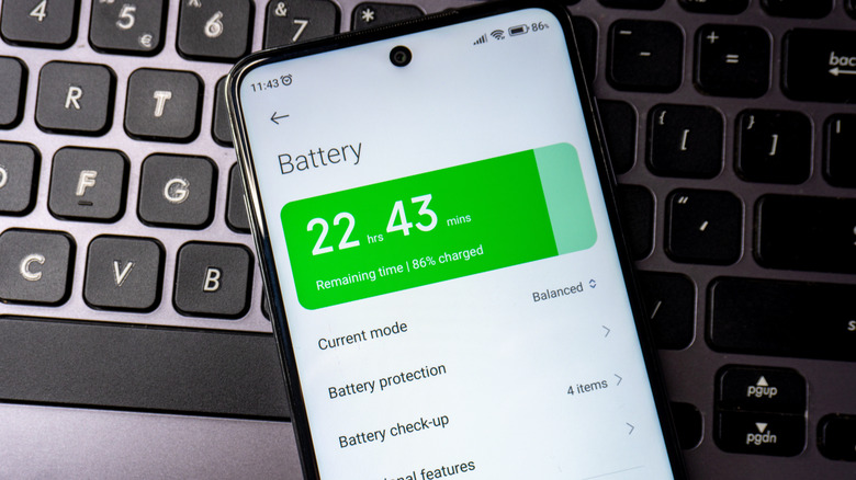 A phone atop a keyboard showing battery health.