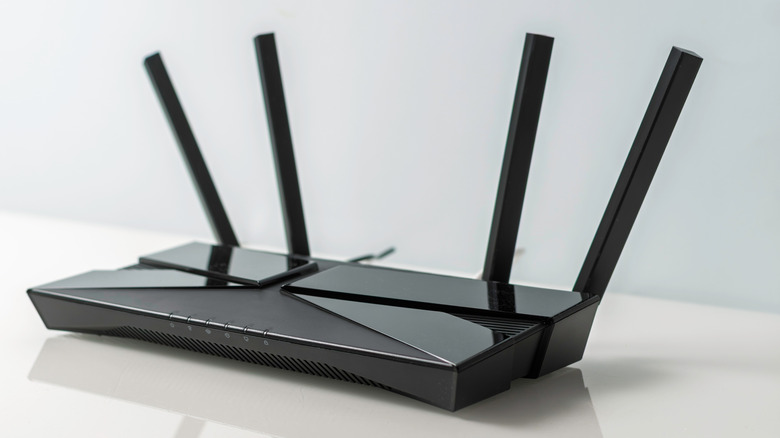 Black Wi-Fi router with four antennas on a glossy table.