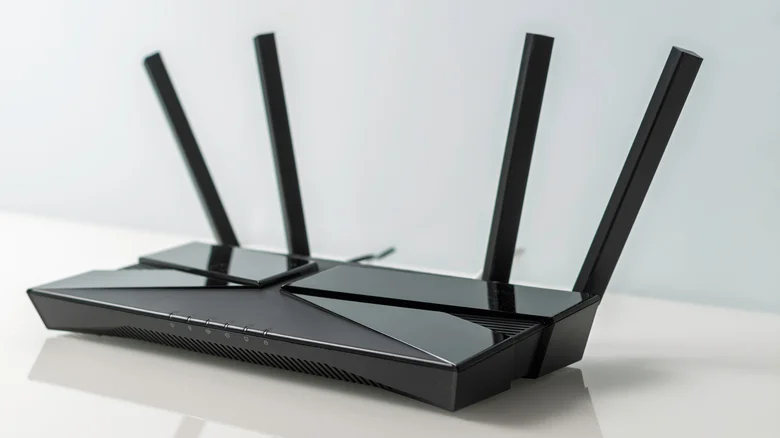 Black Wi-Fi router with four antennas on a glossy table.