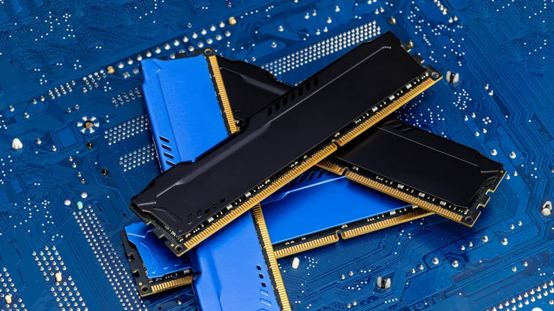 Four DDR memory chips in different colors lying on a blue printed circuit board.